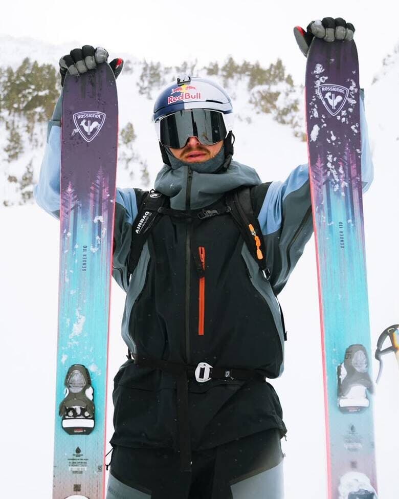 A skier in full Rossignol kit holding up the Sender skis, the Road to Winter grand prize
